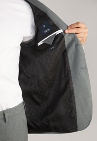 Grauer Slim-Fit-Blazer mit gefüttertem inneren Futter in Schwarz mit Muster, weißen Nähakzenten und einem Etikett mit den Aufschriften "JOOP!" und "SLIM FIT".