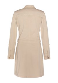 Robe en coton beige avec manches longues, taille ceinturée et épaulettes. Présente une coupe droite avec un détail de couture dans le dos.