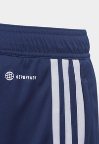 Pantalones cortos deportivos marinos con rayas verticales blancas, una cinturilla elástica y un logo en relieve que dice "AEROREADY". Textura de tela suave.
