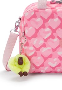 Rosa mönstrad väska med mjuk textur, prydd med en nyckelring i form av en apa i gult och brunt, fäst med en silverkedja.