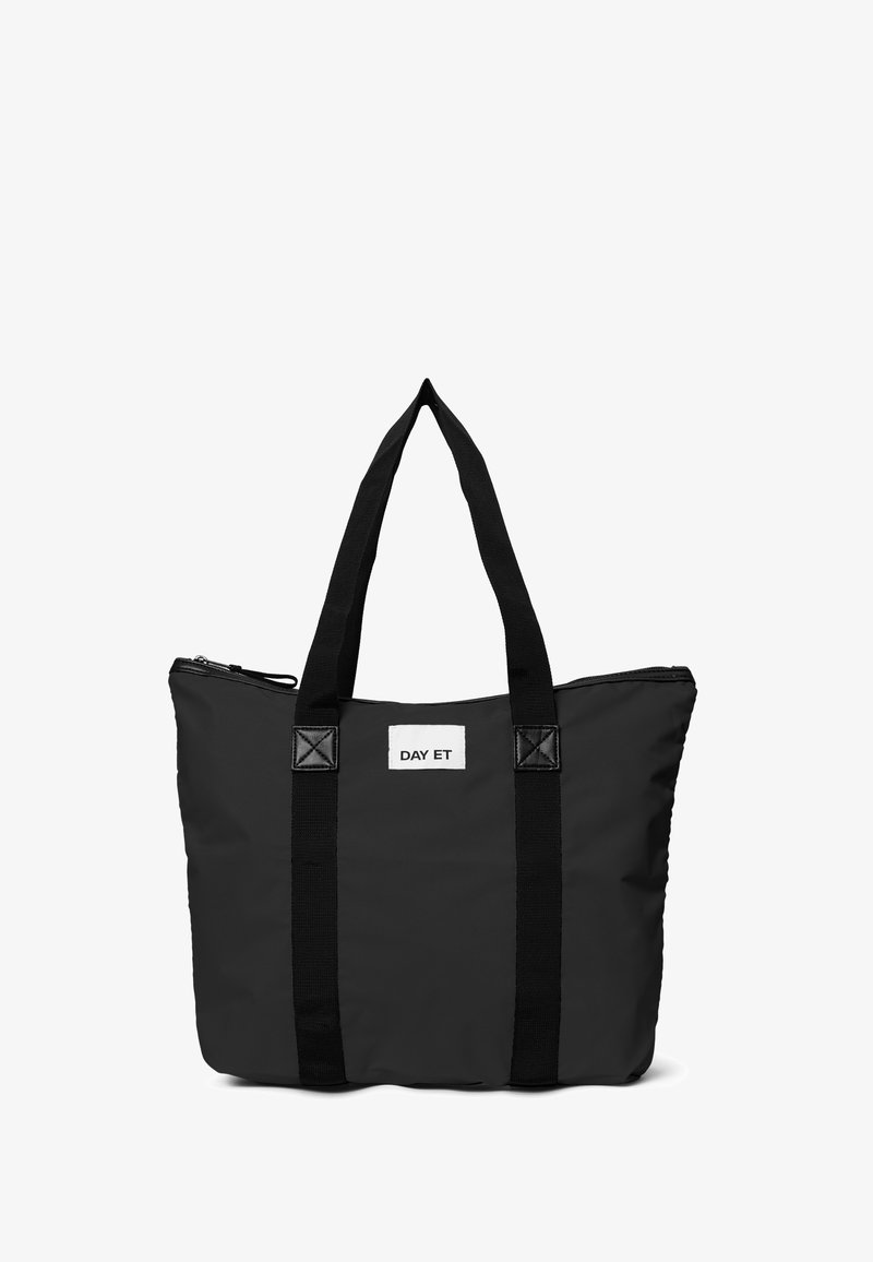 Sac fourre-tout noir en nylon avec deux poignées noires solides, fermeture éclair, et une étiquette rectangulaire blanche portant le logo "DAY ET" sur le devant.
