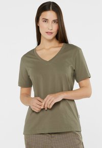Olive green v-neck t-shirt made of cotton, with short sleeves and a relaxed fit. Features minimal stitching and a small brand label on the side.