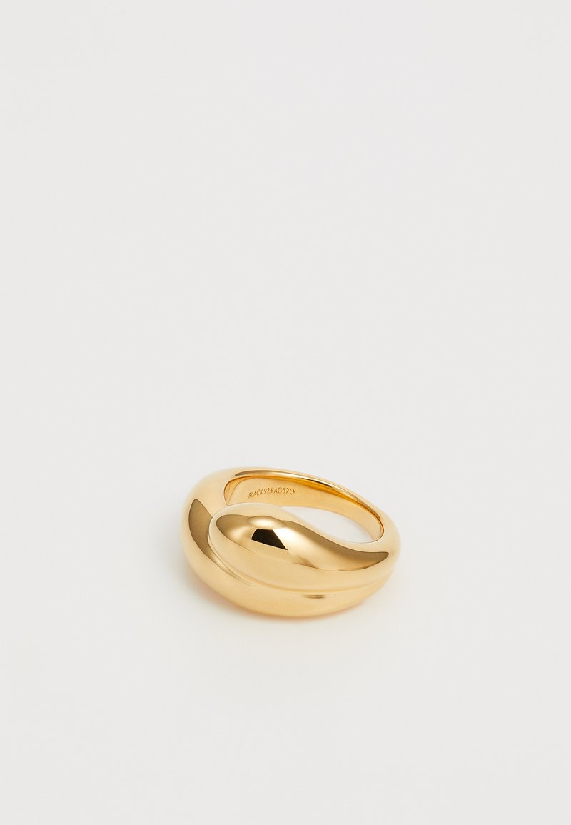 Gold-plated ring with a smooth, curved design. Features a shiny surface, featuring a distinctive asymmetrical shape and a textured inner band.
