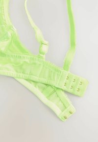 Limegrünes Mesh-Bralette mit verstellbaren Trägern und Haken- und Ösenverschluss; verfügt über einen Rüschensaum und schlanke Träger für ein leichtes Design.