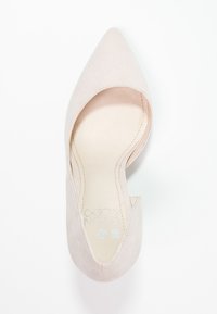 Beige mockaskpumps med spetsig tå, utskärningar på sidorna och en mjuk innerfoder. Designen har minimalt med sömmar och en smal form.