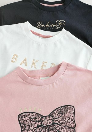Trois t-shirts en noir, blanc et rose, avec un col rond. Les chemises blanche et rose affichent "BAKER" imprimé en doré, avec un motif floral sur le rose.