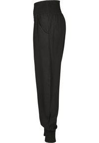 Pantalon noir avec taille smockée, poches latérales et poignets fuselés. Fabriqué en tissu léger, avec une texture douce et une coupe décontractée.