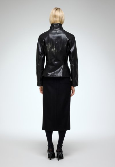 Black leather jacket with a high collar and structured fit, paired with a long black skirt and high-heeled shoes. Smooth texture.