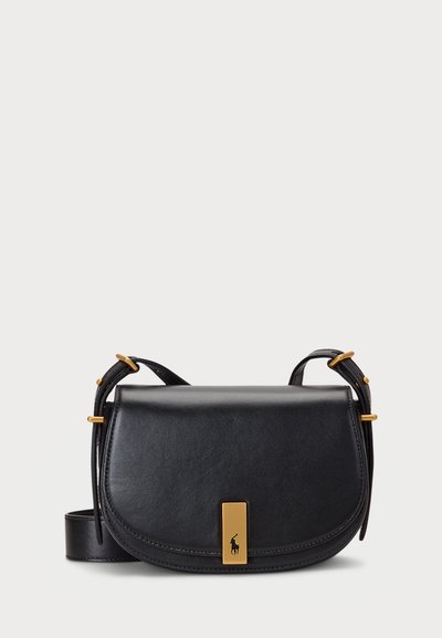 Sac en cuir noir à bandoulière croisée avec une forme courbée, matériel en ton or et un détail en plaque à l'avant portant le logo. Sangle ajustable incluse.