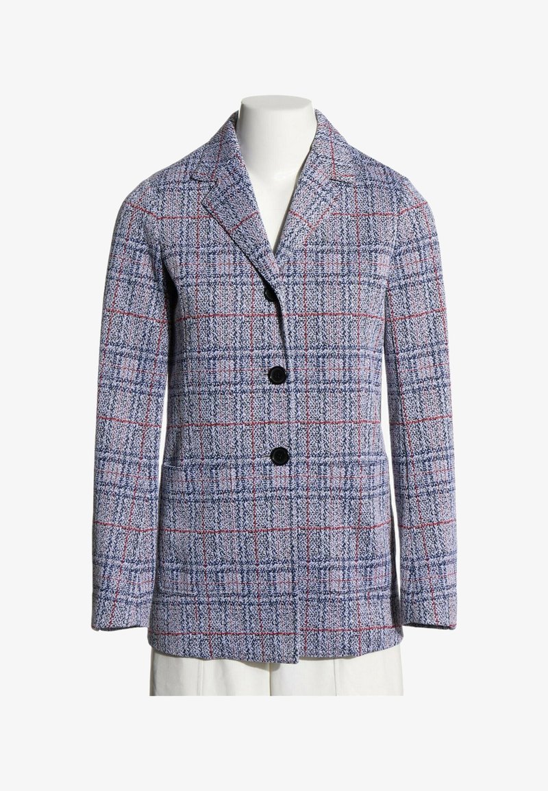Veston texturé à carreaux bleus et rouges avec revers à encoche et deux boutons noirs sur le devant, présenté sur un buste de mannequin blanc.