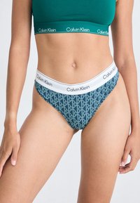 Calvin Klein trossor av bomullsblandning i mörk teal med geometriskt mönster. Har en kontrasterande vit midjeband med logotyp. Slät textur, modern passform.