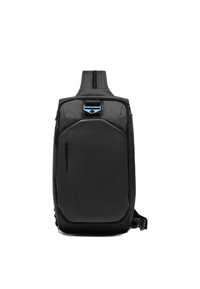 Mochila tipo bandolera negra con un panel frontal texturizado, detalles lisos, cremallera superior y un clip azul. Diseño compacto y duradero con correa ajustable.