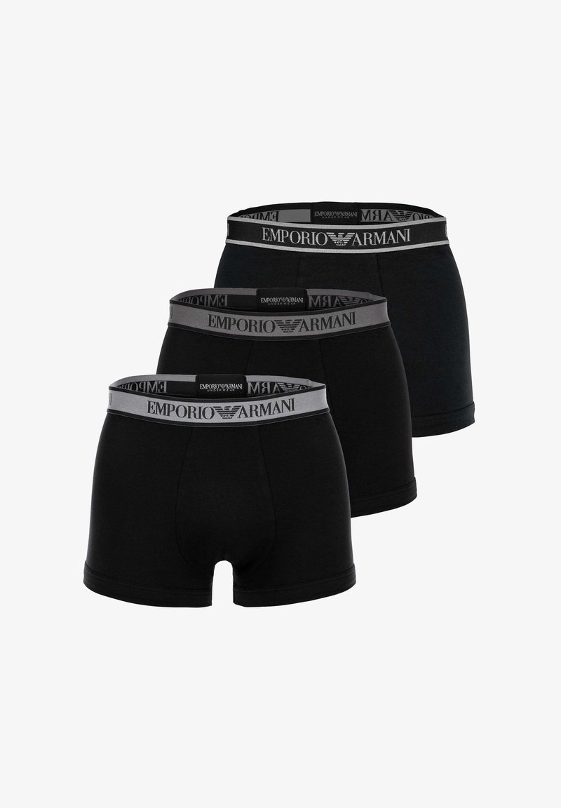 Drei schwarze Emporio Armani Boxershorts mit grauen elastischen Bundbändern, die das Markenlogo zeigen, in einer versetzten Reihe angeordnet.