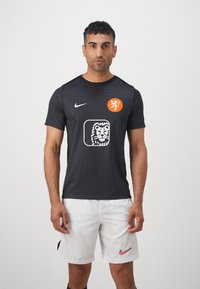 Svart kortermet jersey med prikkemønster, med oransje løvevesen og hvit løvegrafikk. Parret med hvite shorts, Nike-logo på begge.
