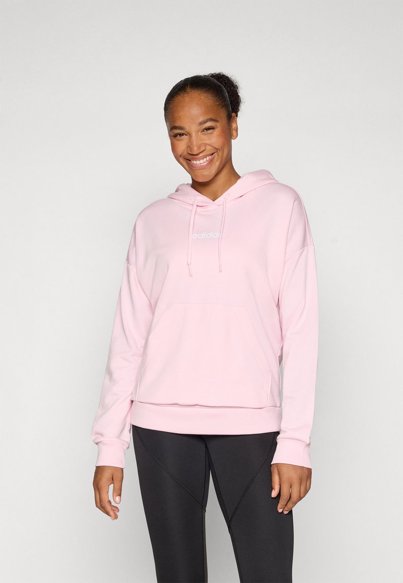 Rosa hoodie i mjukt material med en framficka, dragsko vid huvan och broderad logga. Matchad med svarta leggings.