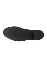 Bruine suède schoen met een zwarte rubberen zool, voorzien van horizontale ribbels en een gestructureerd grip patroon. Afgeronde neus en minimalistisch design.