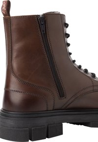 Bota de combate de cuero marrón con cremallera lateral, parte delantera con cordones, suela texturizada y detalles de costura en contraste. Talón y punta reforzados.