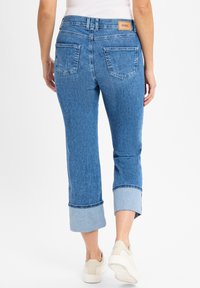 Lichtblauwe denim jeans met een cropped ontwerp, opgerolde manchetten en achterzakken. Beige label op de tailleband; soepele textuur; relaxte pasvorm.