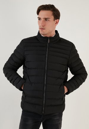 Černá péřová bunda s vysokým límcem, prošívaným designem, zipovým zapínáním a bočními kapsami. Hladký povrch s minimem švů.