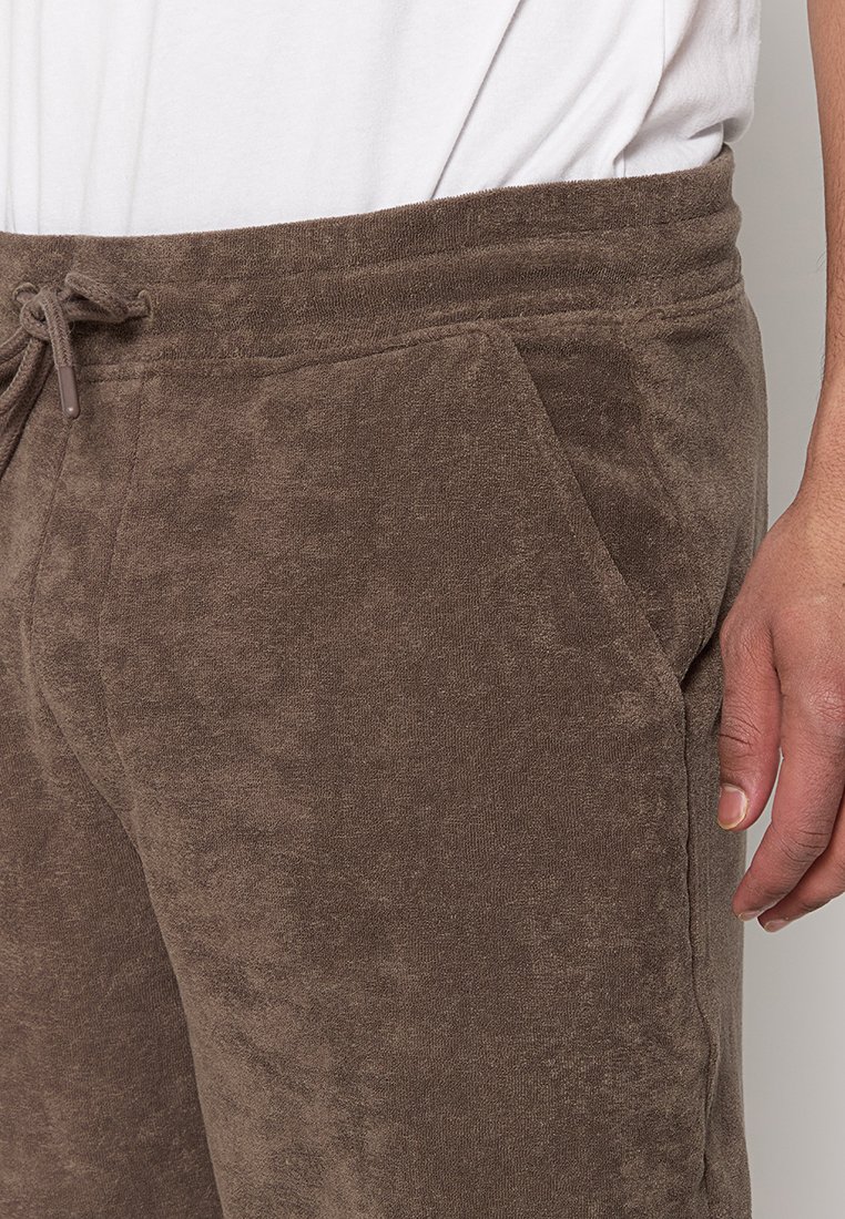 Braune Fleece-Jogginghosen mit einer weichen Textur, ausgestattet mit einem elastischen Bund und Kordelzug sowie seitlichen Taschen.