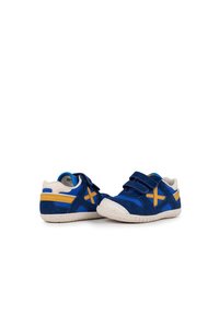 Zapatos de gamuza azul con acentos amarillos y crema, con cierre de Velcro, suela texturizada y costuras contrastantes. Diseño de punta redondeada.