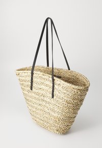 Geflochtene Strohtasche mit schwarzen Ledergriffen. Sie verfügt über ein geräumiges, offenes Top und ein strukturiertes, natürliches Finish. Gebogene Form, leichtes Design.