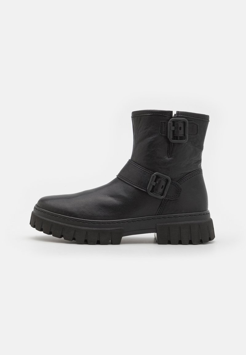 Botas negras hasta el tobillo hechas de cuero suave con una suela gruesa y estriada, que presentan dos hebillas laterales y un diseño de punta redondeada.