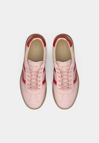 Sneakers in camoscio rosa con accenti rossi, dotate di chiusura con lacci e suola in gomma. L'interno ha una finitura beige con dettaglio logo.