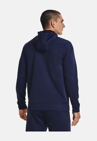 Marineblå hættetrøje, blødt stof, tætsiddende design med lange ærmer og ribbede manchetter, med en flad kant og glat tekstur.