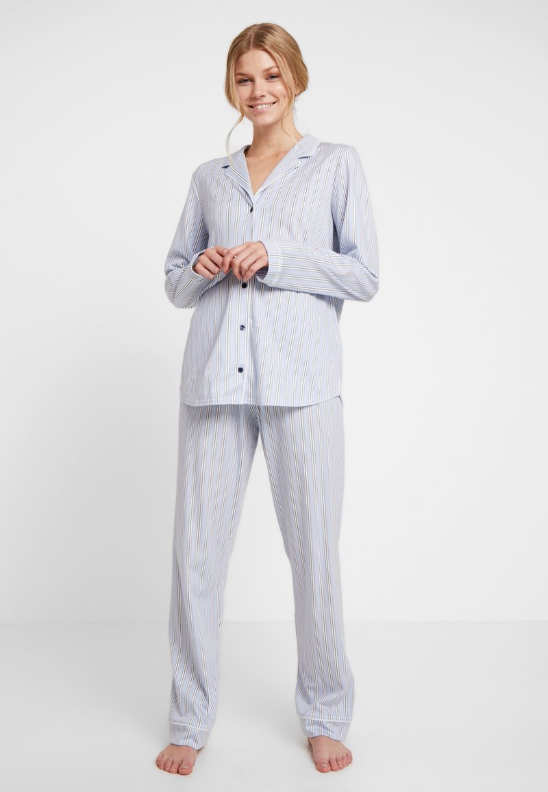 Blå randig pyjamas med lång ärm, knappar och lösa byxor; mjukt tyg och avslappnad passform. Accentuerad med subtila gula ränder.