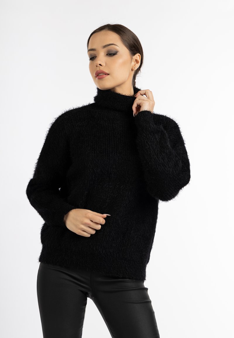 Schwarzer, flauschiger Rollkragenpullover mit langen Ärmeln und lockerem Schnitt. Der Stoff hat eine weiche Textur, die Wärme und Komfort bietet.