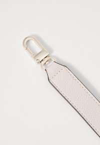 Ljusbeige läderrem med texturerad yta, utrustad med ett clasp i guldton och mörkbrun kantstickning.