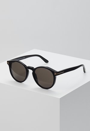 Black round sunglasses with dark lenses, featuring a glossy finish, gold metal accents on temple, and a sleek design.