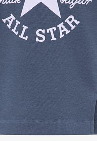 Mørkeblå bomull T-skjorte med en stor hvit stjerne og teksten "ALL STAR". Har en glatt tekstur og kortermede ermer, med en rett kant.