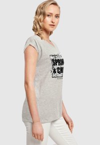 Grå afslappet t-shirt med korte ærmer, prydet med et blomsterdesign og fed tekst. Behagelig pasform, lavet af blødt stof.