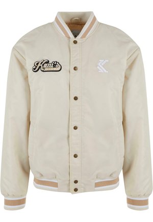 Beige bomber dzseki két elülső zsebel, patentos gombokkal, bordás mandzsettával és gallérral. Kiemelkedik a hímzett "Kani's Diner" felirattal és logóval.