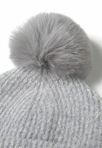 Harmaa neulottu pipo, jossa on pehmeä, pörröinen harmaa pom-pom päällä. Sisältää ribbin tekstuurin, joka korostaa eri neulekuvioita.