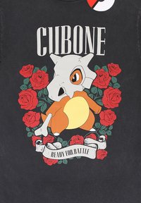 Zwart t-shirt met een cartoonfiguur met een schedelachtig hoofd, een oranje lichaam, omringd door rode rozen en een lint met de tekst "KLAAR VOOR DE STRIJD."