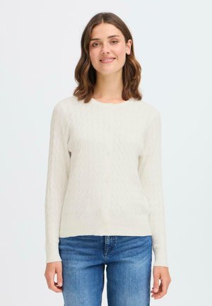 Lys kremfarget cardigan med et teksturert strikkemønster, hellange ermer og knappelukking. Sammen med blå denimjeans.