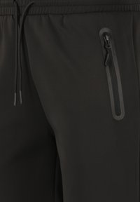 Svarta joggerbyxor i ett mjukt material, med elastisk midja, snörning och en ficka med dragkedja i en stilren design.