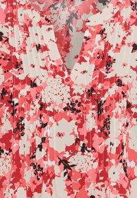 Blumenbluse in Pink, Rot und Creme mit einem V-Ausschnitt. Verfügt über Falten und schwarze Akzente. Zusammensetzung deutet auf einen leichten Stoff hin.