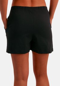Czarne szorty z elastycznym pasem i bocznymi kieszeniami, wykonane z miękkiego, lekkiego materiału. Gładka faktura i casualowy design.