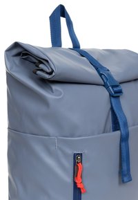 Zaino grigio a sacco realizzato in materiale resistente, con una tracolla blu, un accento di corda arancione e una tasca laterale con zip.