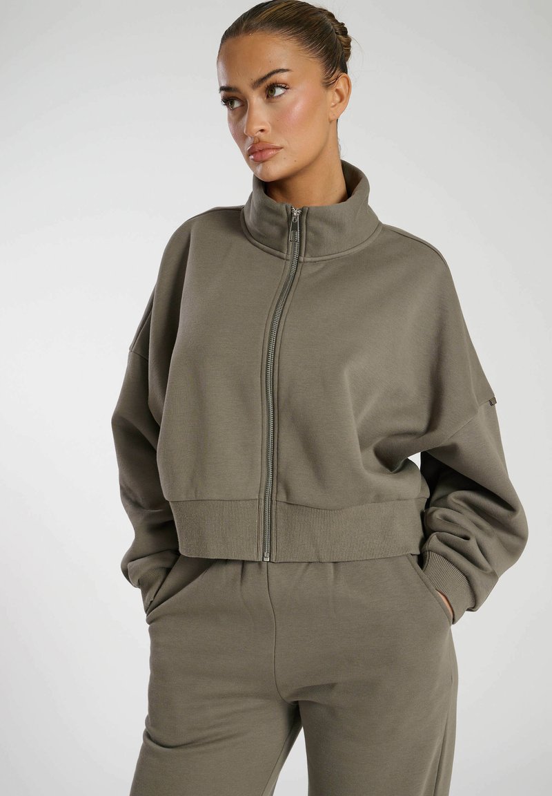 Olijfgroene cropped sweatshirt met hoge hals, voorrits, geribde zoom en verlaagde schouders. Glad materiaal met een ontspannen pasvorm.
