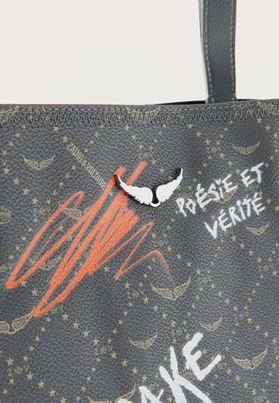 Μαύρη υφασμάτινη τσάντα με καφέ σχέδια φτερών, κεντρικό λευκό κούμπωμα σε σχήμα φτερού, πορτοκαλί μουτζούρα και λευκό κείμενο "POÉSIE ET VÉRITÉ" στην επιφάνεια.