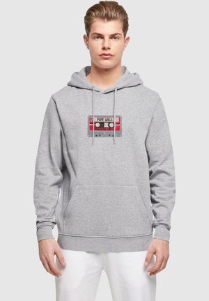 Gray hoodie made of soft fabric featuring a front pocket and a graphic design of a cassette tape with red and black accents.