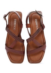 Sandalias de cuero marrón con un diseño de tiras trenzadas. Cuenta con hebilla ajustable en el tobillo y suelas planas; forma cuadrada minimalista en la punta.