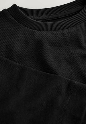 Melns džemperis ar ribveida apkakli un apakšmalu, teksturētu audumu un tīrām šuvju detaļām, kas izceļ gludu, matētu virsmu.