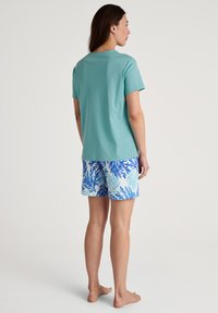 Light teal short-sleeve top paired with patterned shorts featuring blue coral designs on a white background. Comfortable fit, soft material.