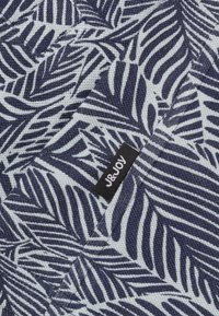 Marineblauwe en witte stof met een bladmotief, met een geweven textuur; bevat een zwart label met witte tekst "J&JOY."